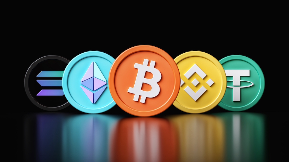 Colorized crypto coins standing up on a black back drop
